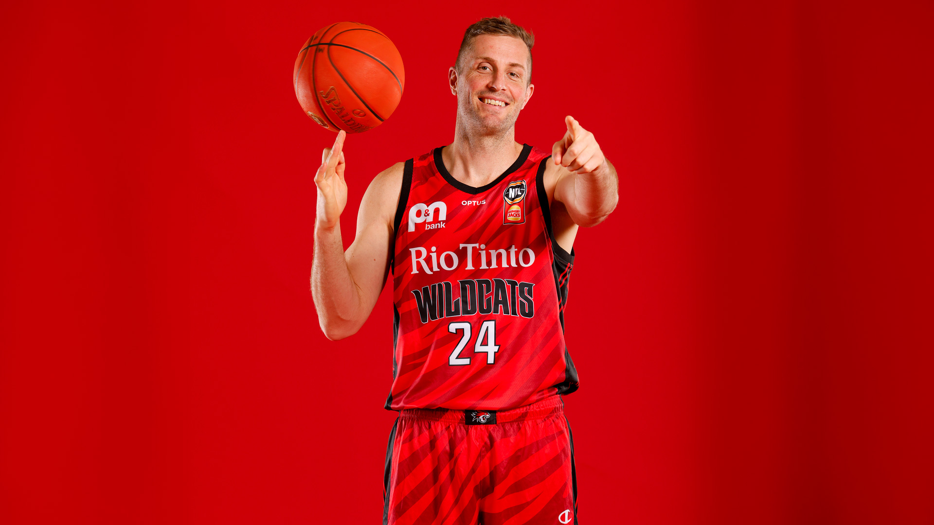 Basketball player wearing red jersey and holding a ball posing for the camera