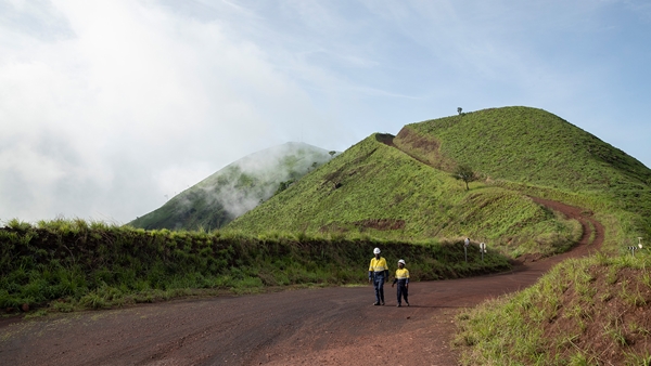 Two employees walking along a dirt path in Simandou