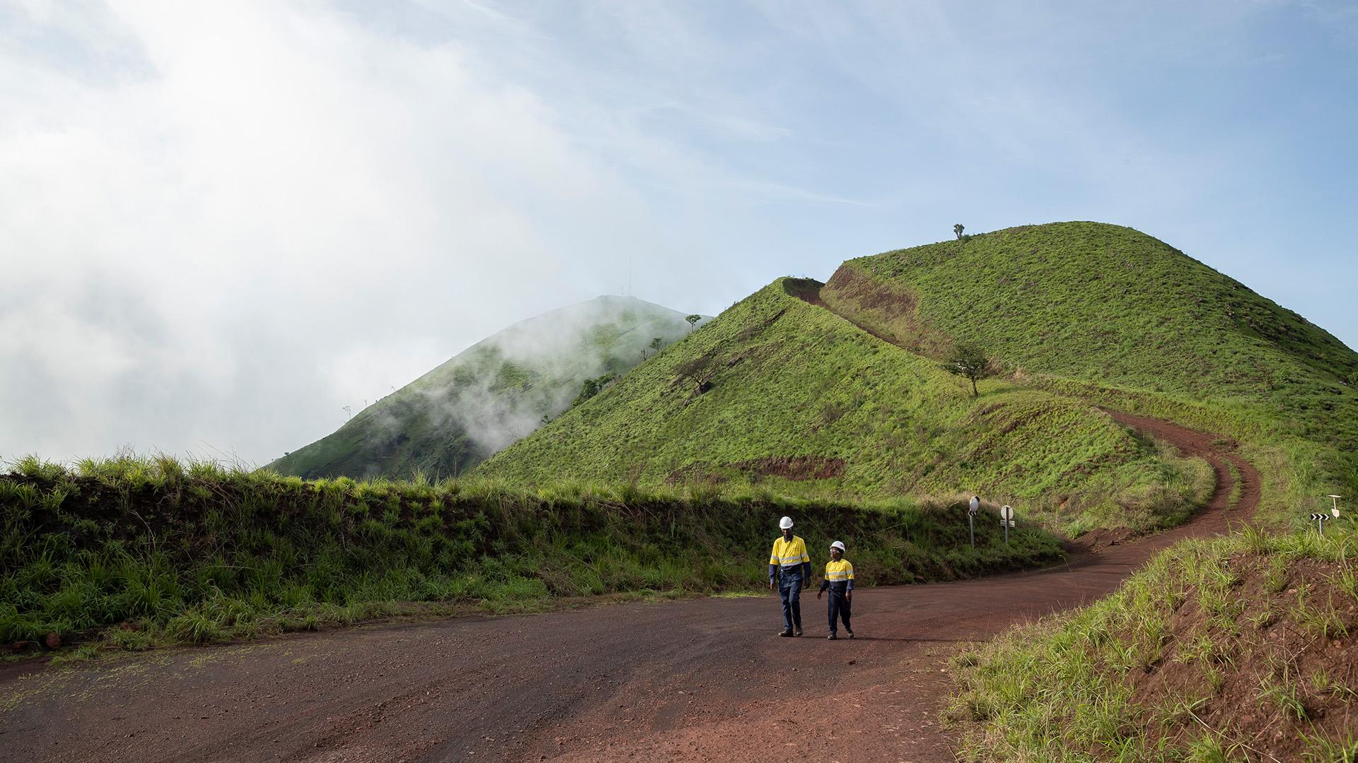 Two employees walking along a dirt path in Simandou