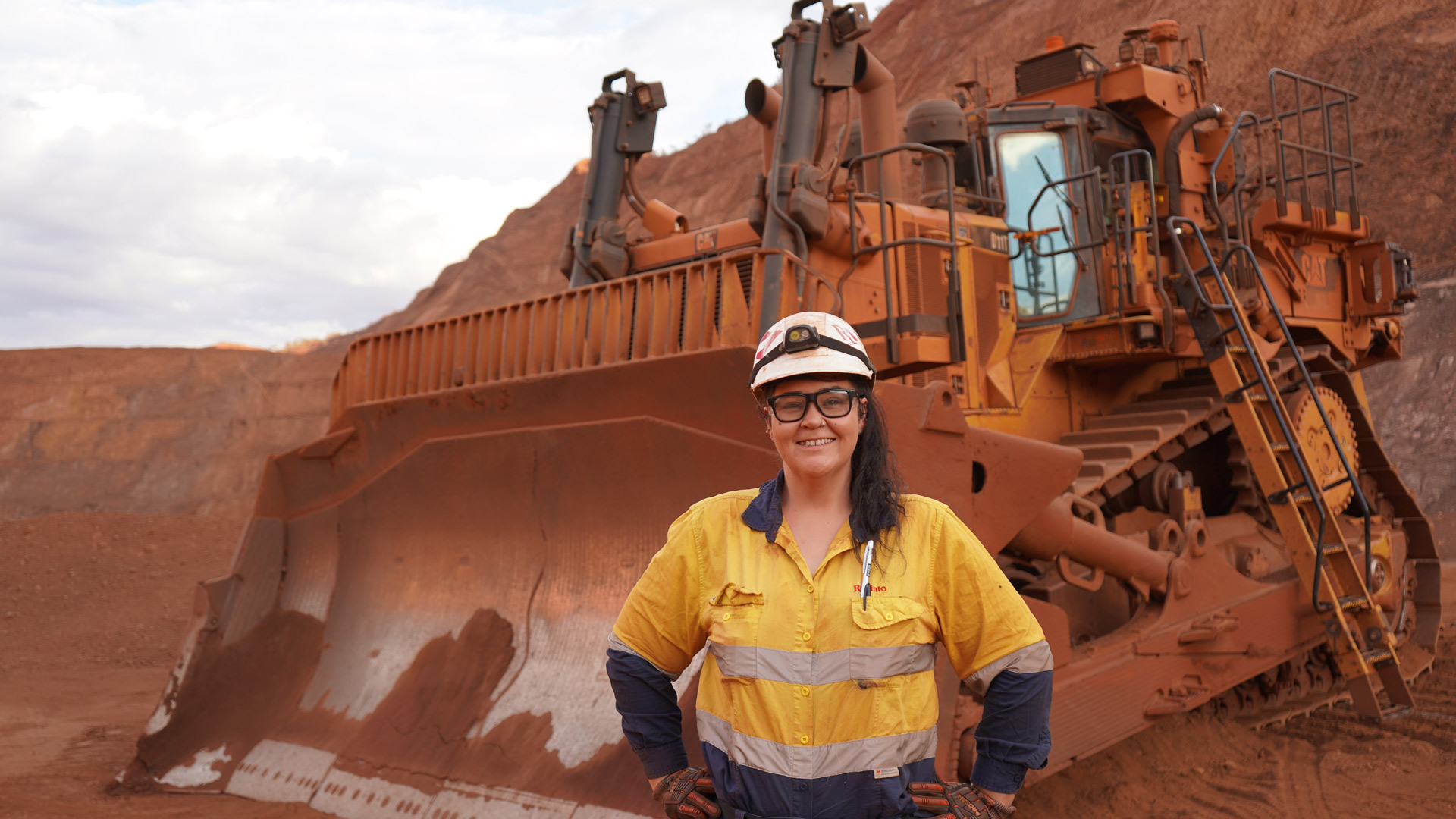 Jodie standing in front of bulldozer at a mining site