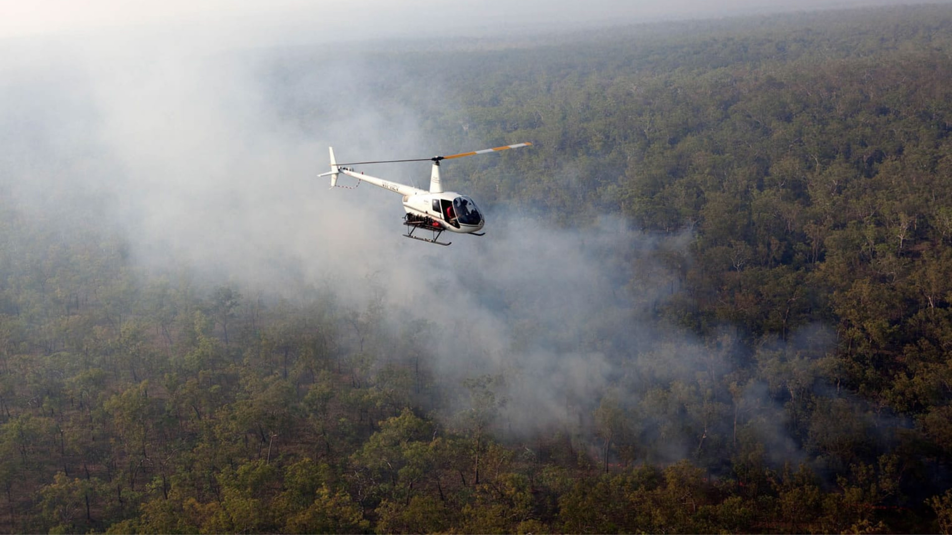 Helicopter flying over a burning forest in Arnhem Land, Northern Territory, Australia.  