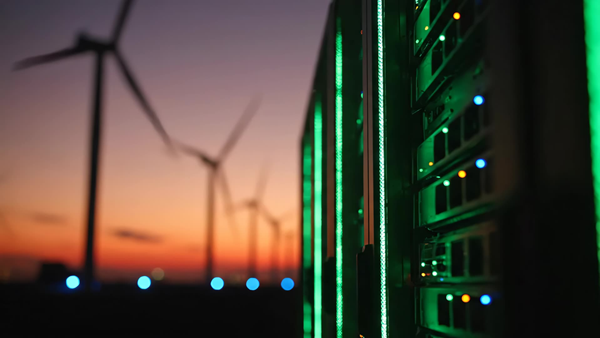 Server racks illuminated in green beside a wind farm at sunset, representing renewable energy and digital infrastructure as Rio Tinto's dual drivers.