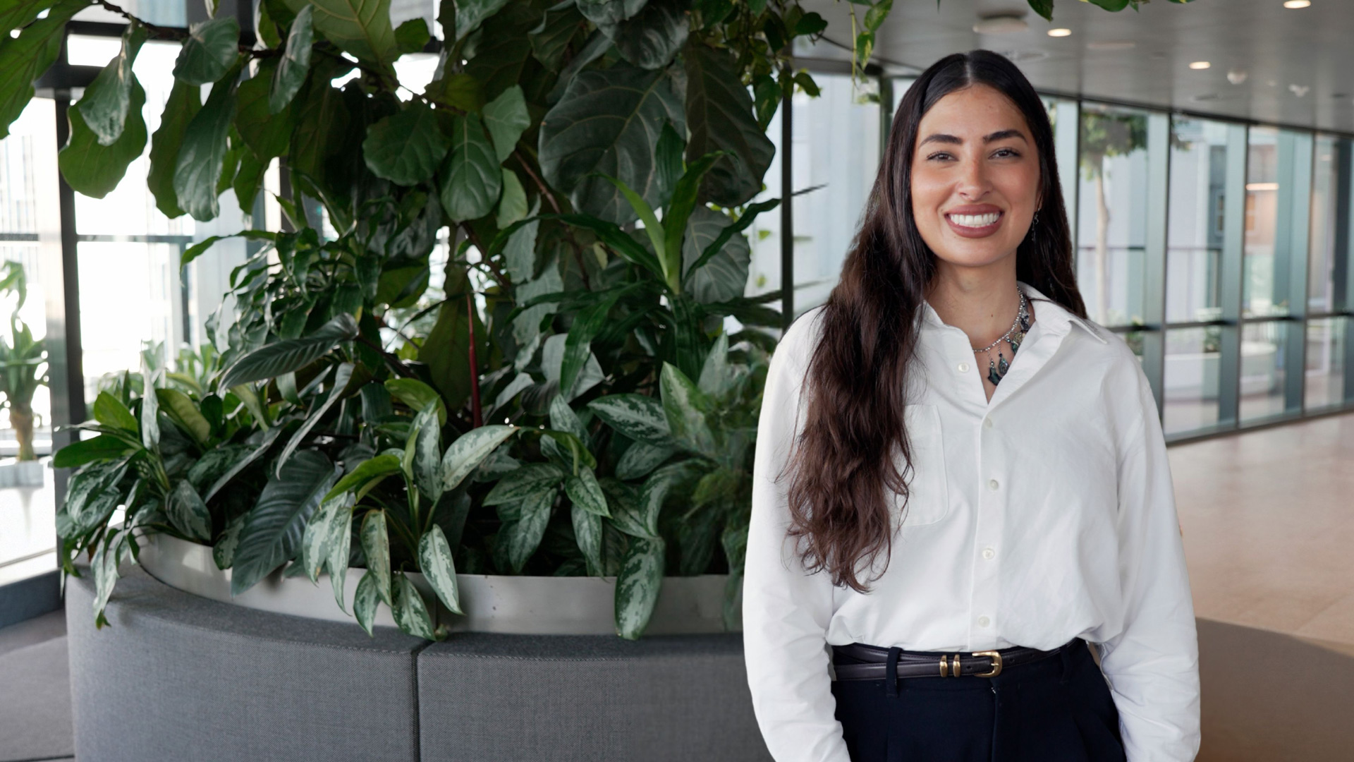 Lucy, our Communities and Social Performance Specialist standing in front of indoor plant setting. 