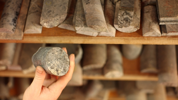 A person holding a piece of material that looks like a cylindrical stone