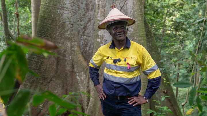 Moussa, Simfer's Cultural Heritage Specialist, stands in front of Le Grande Fromager, a sacred tree in the protected Boyboyba Forest.