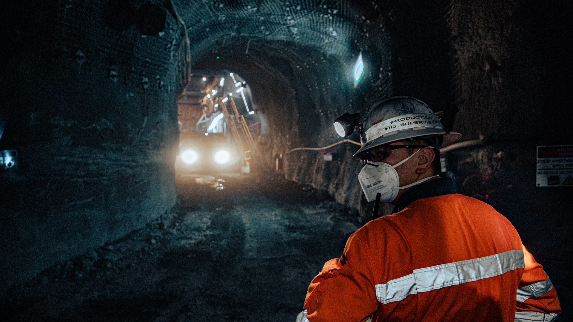 Worker watches a vehicle approach through an underground tunnel.