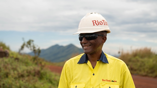 Sidiki, our SimFer's Manager wearing a Rio Tinto branded helmet and uniform and smiling for a portrait shot. 