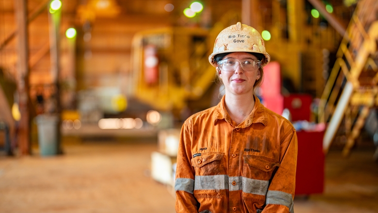 Person wearing a hard hat and safety glasses standing inside an industrial facility.