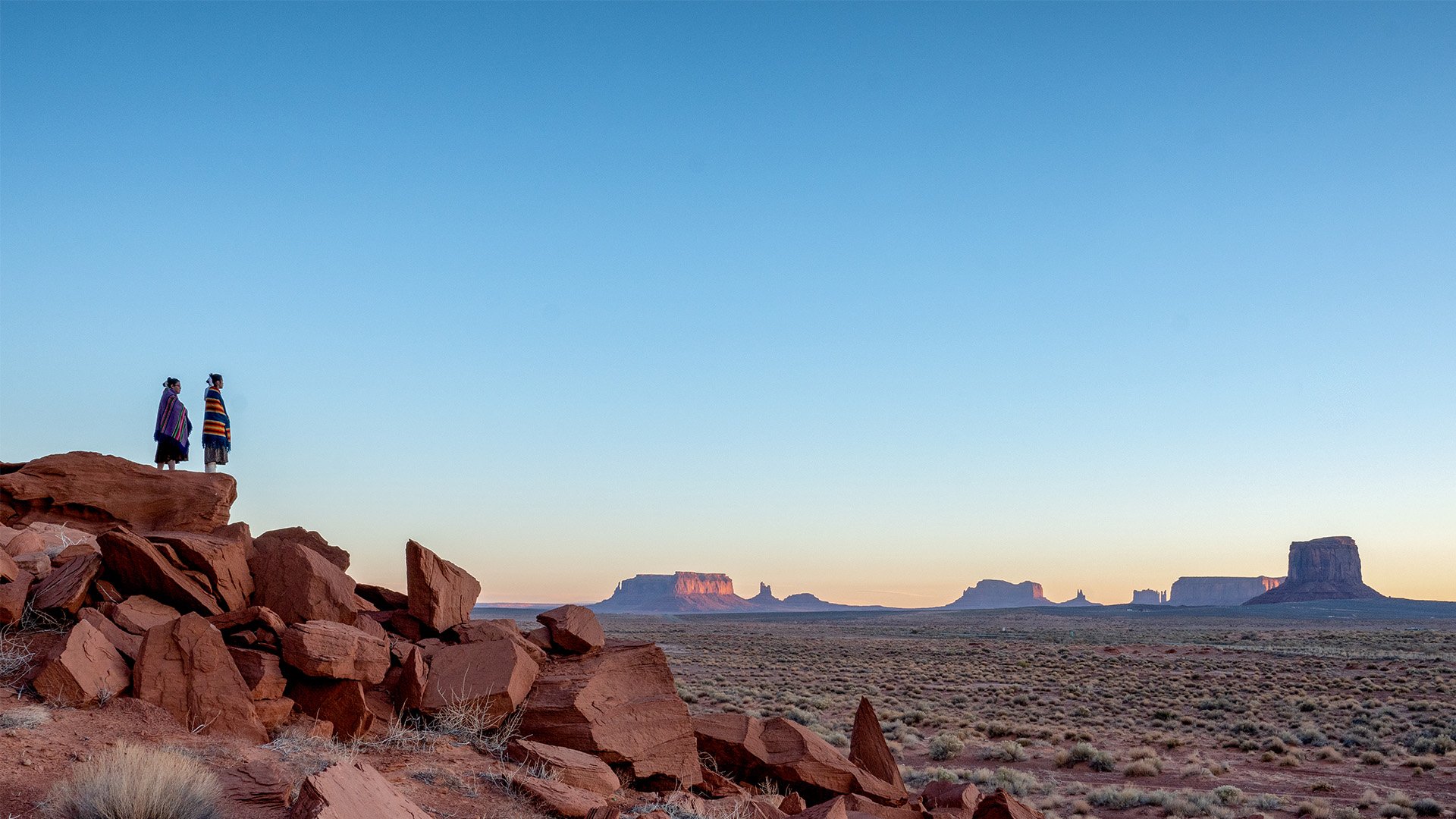 Two people in traditional clothing enjoying the vast US desert and red rock landscape