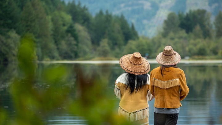 People standing on pier taking in the view of Canada's lake and mountain surrounds.