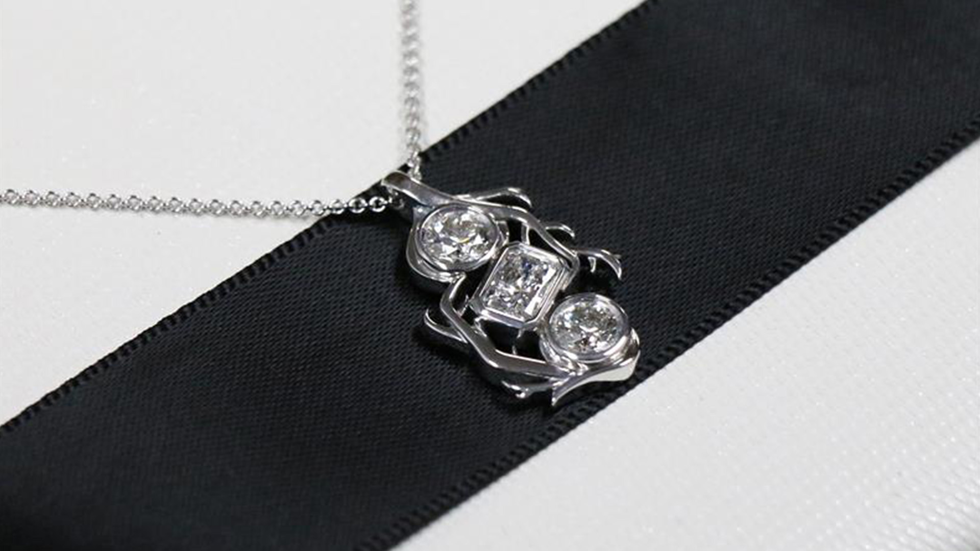 The pendant, set in 18-karat white gold, features a round brilliant-cut 0.41 carat Ekati diamond, a radiant-cut 0.51 carat Gahcho Kué diamond, and a round brilliant-cut 0.41 carat Diavik diamond. 